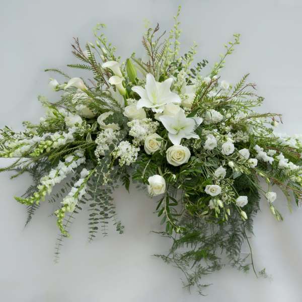 White lilies and roses in a long floral spray with greenery
