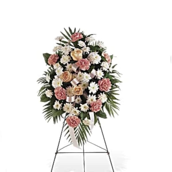 Tall standing spray of white daisies, peach roses, and pink carnations on a metal easel