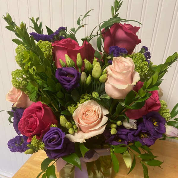 Mixed bouquet of roses and purple blooms in a glass vase