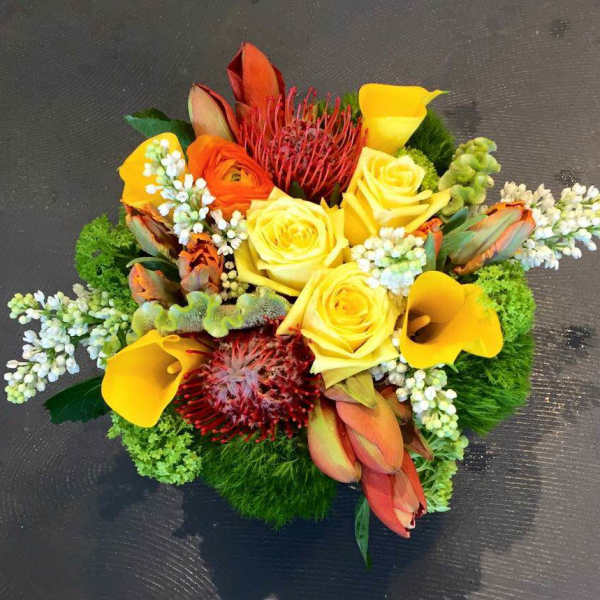 Bright bouquet with yellow roses, calla lilies, and orange tropical flowers