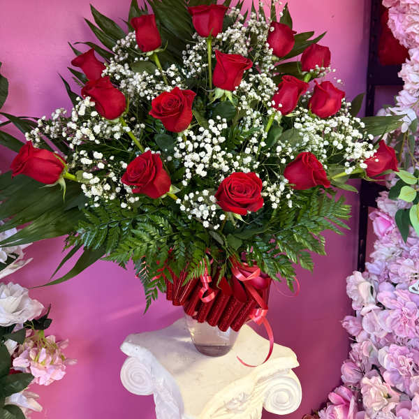 Red roses arranged in a clear vase with white baby's breath