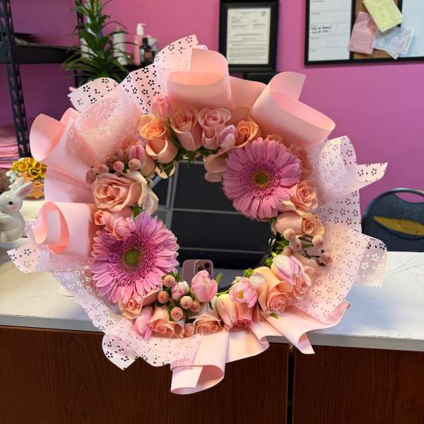 Pink floral wreath with roses and gerbera daisies wrapped in pastel paper