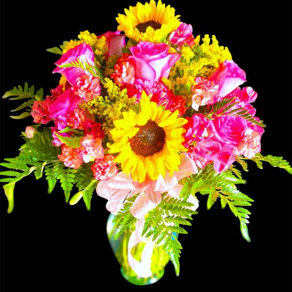 Bouquet of pink roses and yellow sunflowers in a glass vase