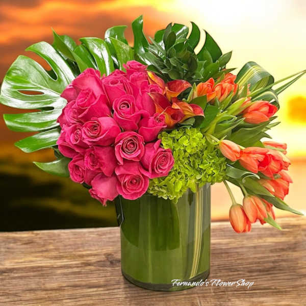 Arrangement of hot pink roses and orange tulips in a green glass vase