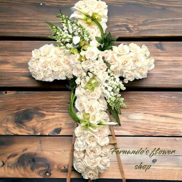Standing cross-shaped spray of ivory roses with green orchids and white spikes on an easel