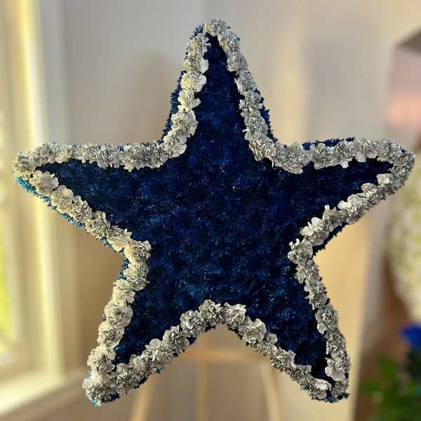 Large blue and white star-shaped standing floral arrangement on a wooden easel