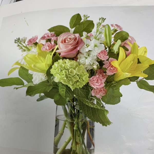 Pink roses and yellow lilies arranged in a glass vase