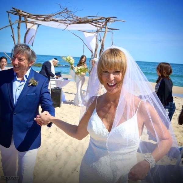 Bride and groom at a beach wedding under a driftwood arch
