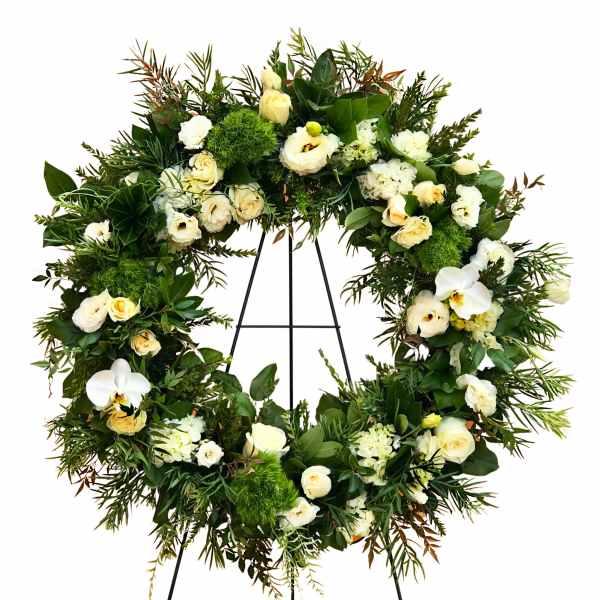 Large floral wreath with white roses and orchids on a black stand