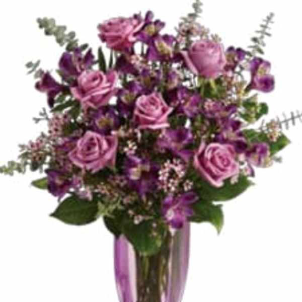 Purple and pink bouquet in a tall glass vase