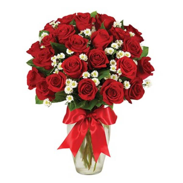 Bouquet of red roses with small white filler flowers in a glass vase