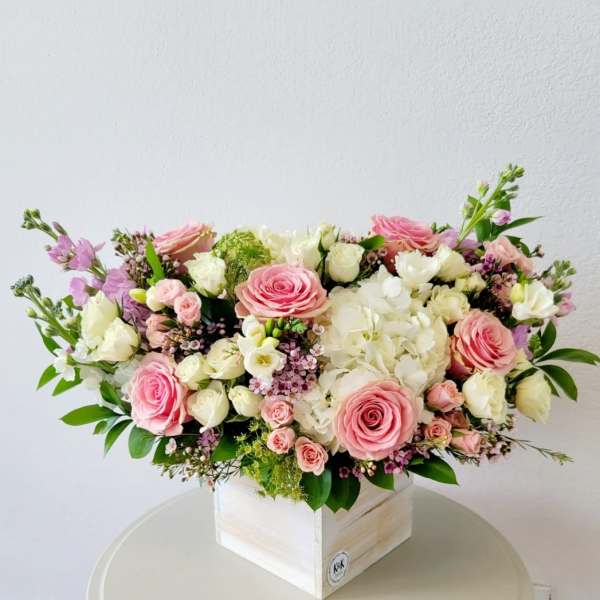 Pink and white rose arrangement in a white wooden box