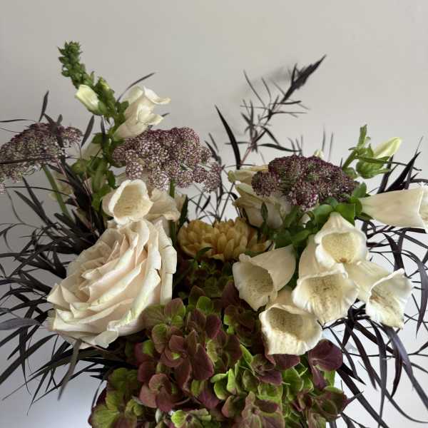Cream roses and foxglove in a mixed floral arrangement