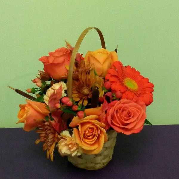 Basket arrangement of orange roses and gerbera daisies