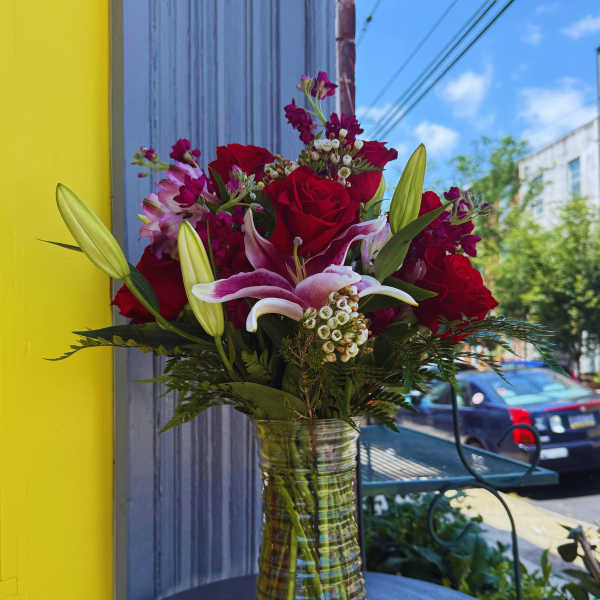 Bouquet of red roses and pink lilies in a clear glass vase