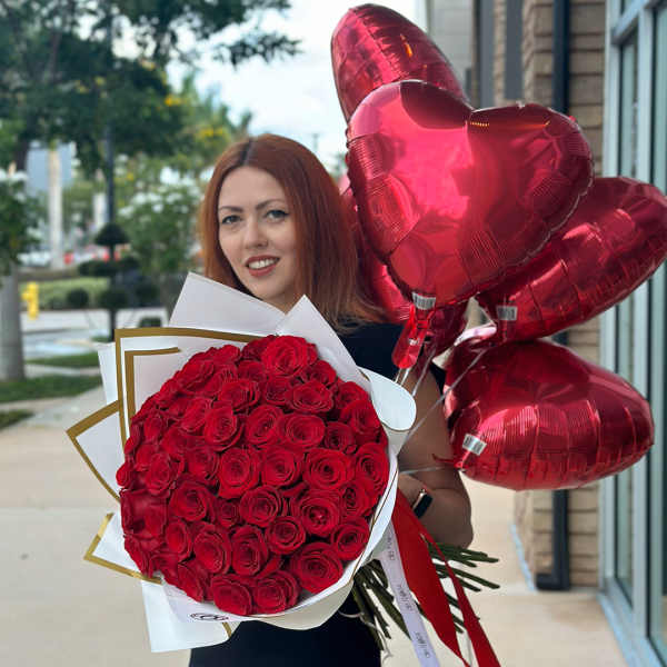 Woman holding a bouquet of red roses and red heart balloons