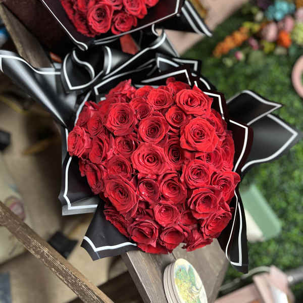 Two bouquets of red roses wrapped in black paper with white trim