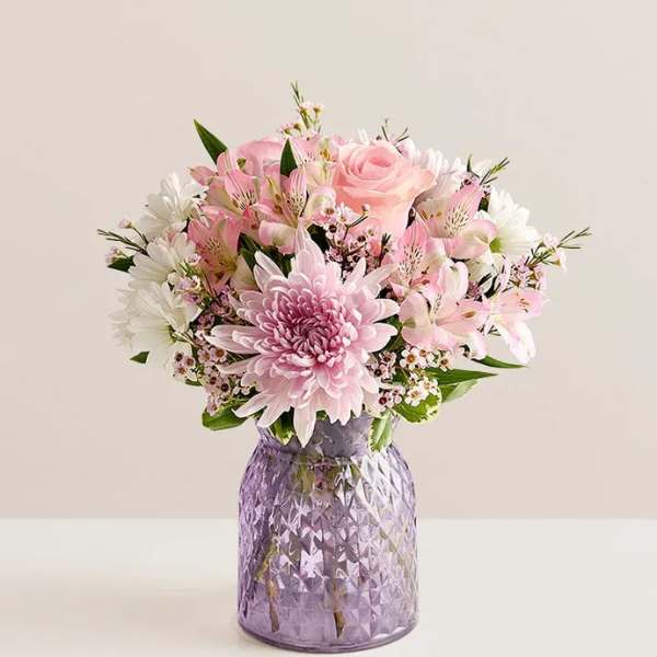 Pink and white bouquet in a purple glass vase
