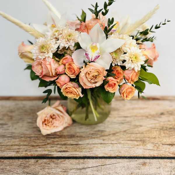 Peach roses and white orchid bouquet in a glass vase