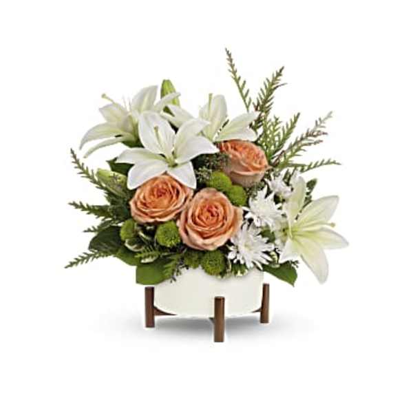 White lilies and peach roses arranged in a white container