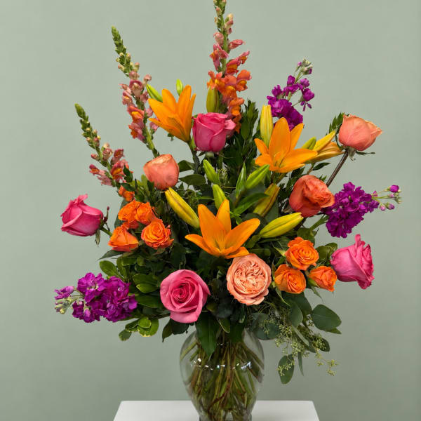 Colorful mixed bouquet in a clear glass vase with roses and lilies