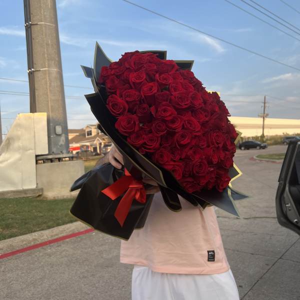 Large bouquet of red roses wrapped in black paper with a red ribbon