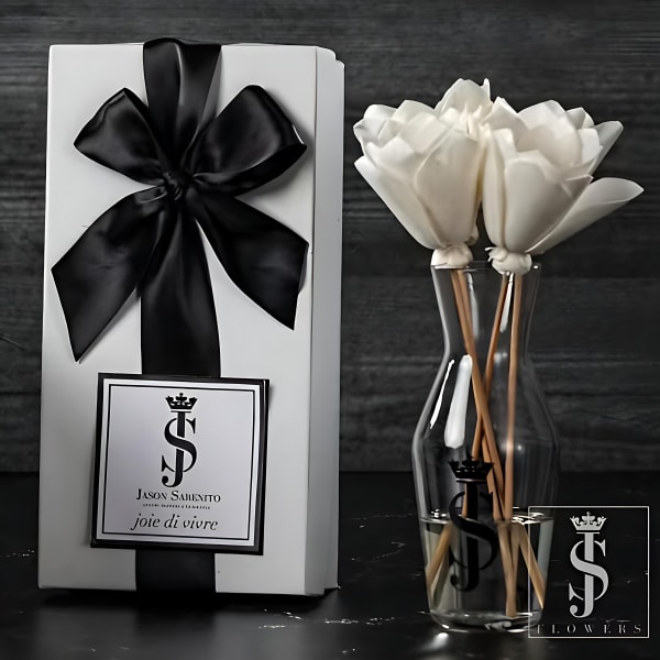 White flowers in a clear vase beside a white gift box with a black ribbon