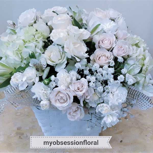 White and pale pink rose bouquet in a white basket