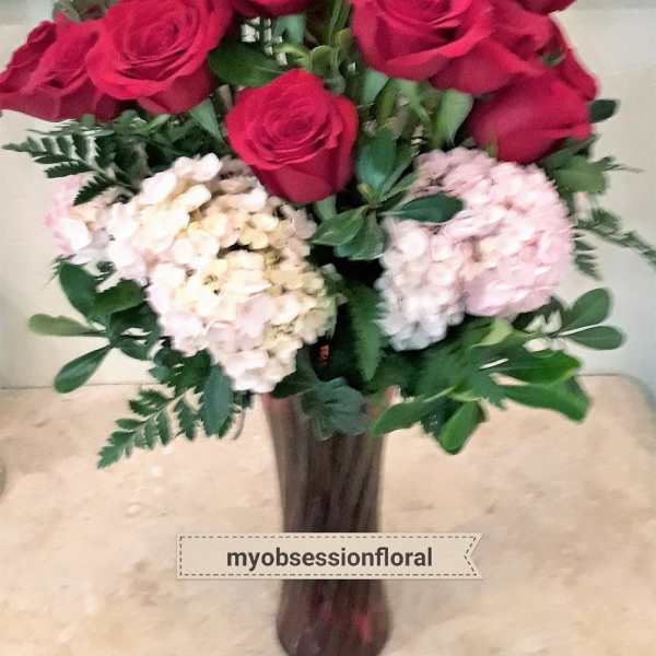 Bouquet of red roses and pale hydrangeas in a tall vase