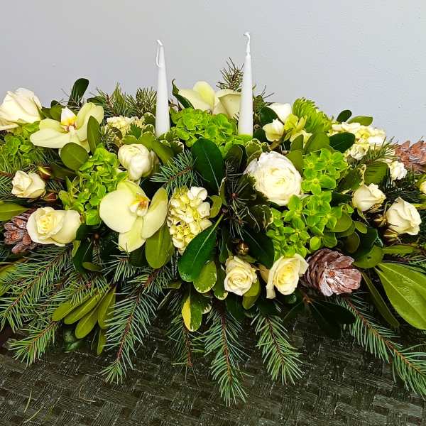 White floral centerpiece with candles and pine greenery