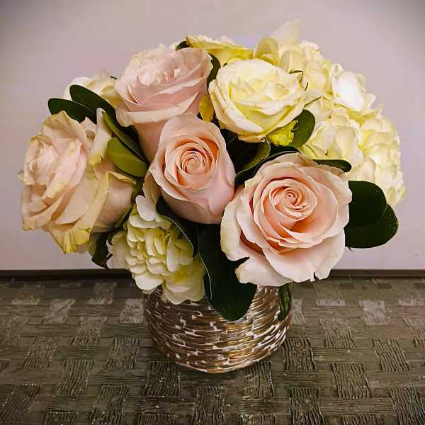 Bouquet of pale pink roses and white hydrangeas in a woven basket