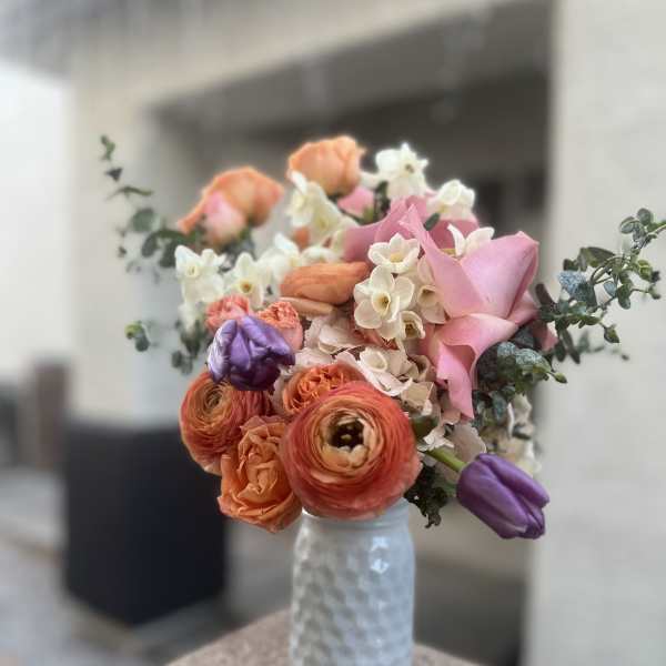 Bouquet of pink, orange, and white flowers in a textured glass vase