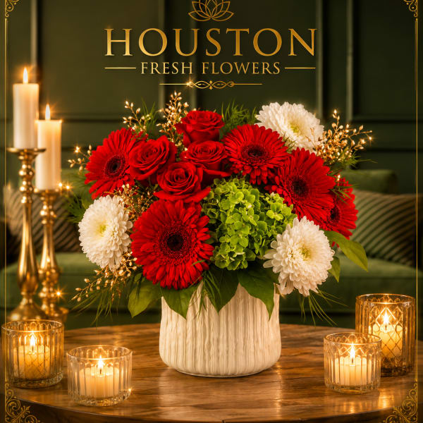 Red and white flower arrangement in a white vase with candles nearby