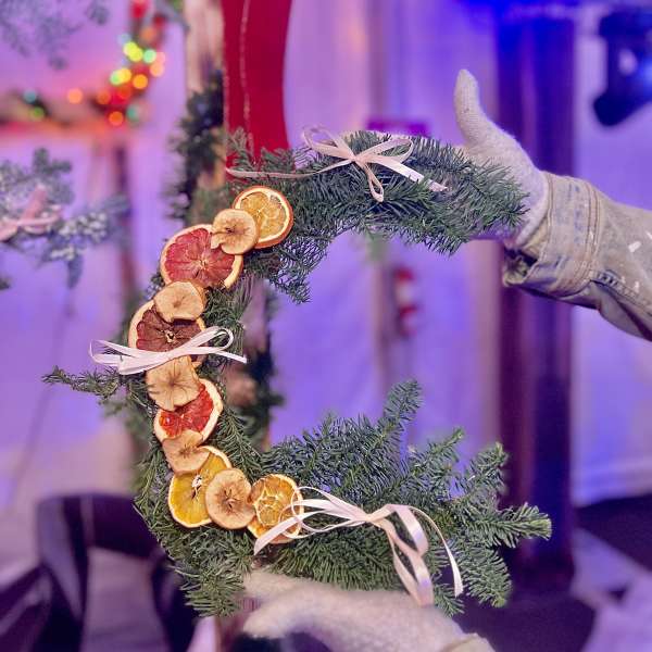 Crescent evergreen wreath with dried citrus slices and pale ribbon bows