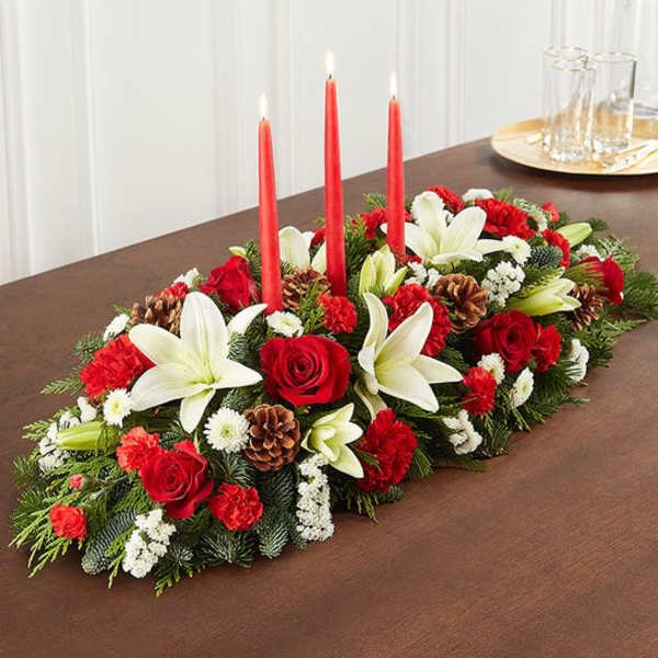 Holiday centerpiece with red candles, white lilies, and red roses