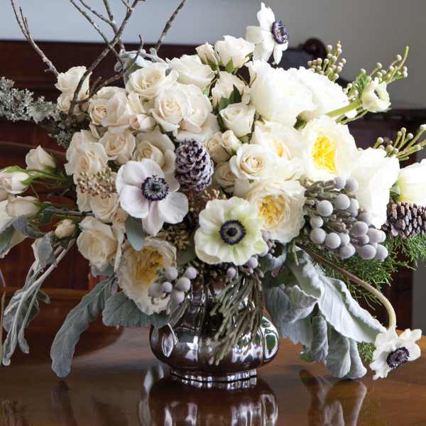 White floral arrangement with roses and anemones in a silver vase