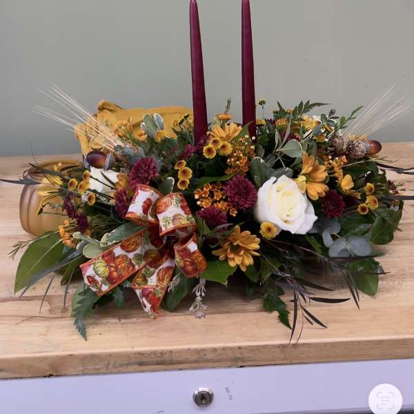 Autumn floral centerpiece with two burgundy candles and a ribbon bow