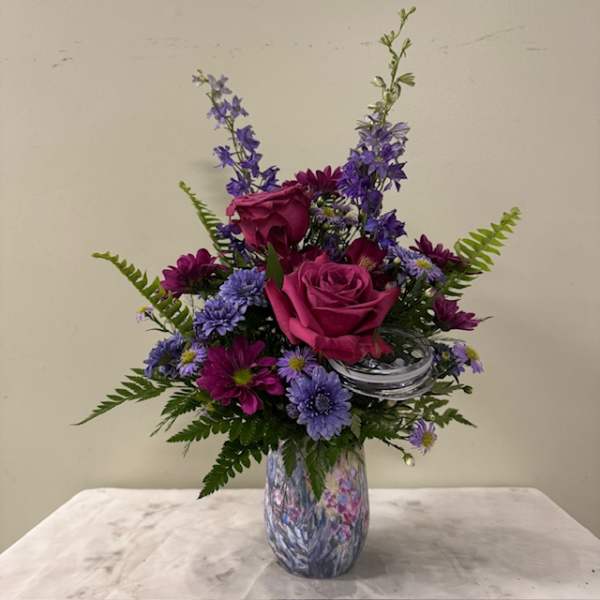 Pink roses and purple flowers arranged in a patterned vase
