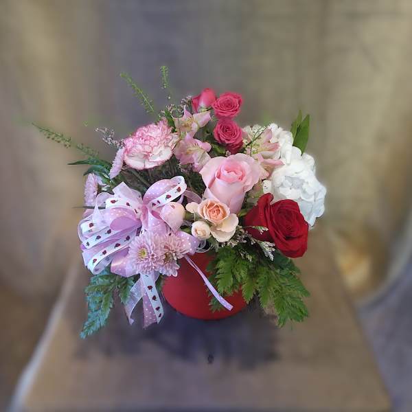 Mixed bouquet in a red hatbox with pink, red, and white flowers