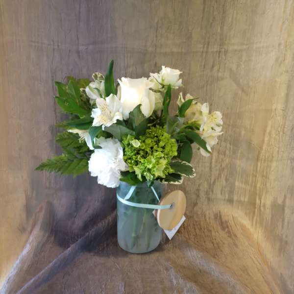 White roses and alstroemeria in a glass vase with green hydrangea