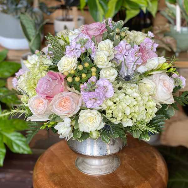 Pink and white roses arranged in a silver pedestal vase
