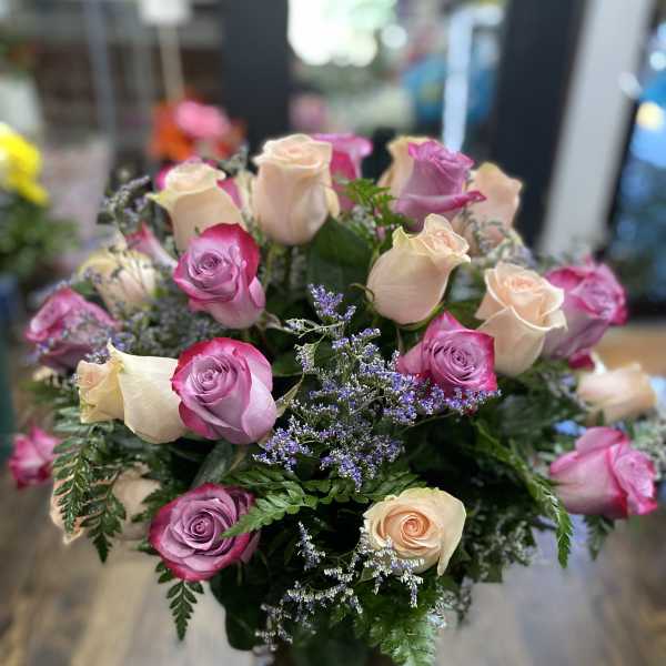 Bouquet of pink and cream roses with purple filler in a glass vase
