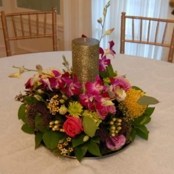 Round floral centerpiece with a gold candle in the middle