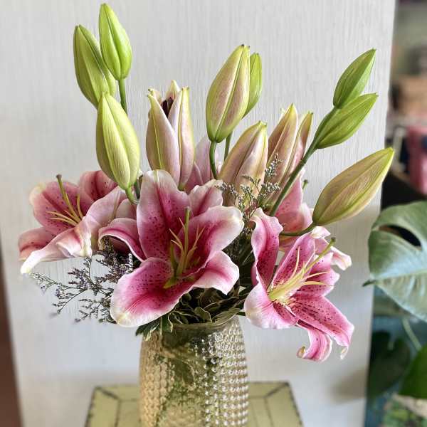 Pink lilies arranged in a textured glass vase