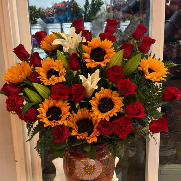 Bouquet of red roses, sunflowers, white lilies, and red carnations in a painted vase