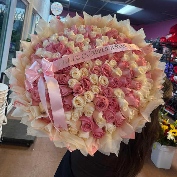 Large bouquet of pink and cream roses with a pink ribbon
