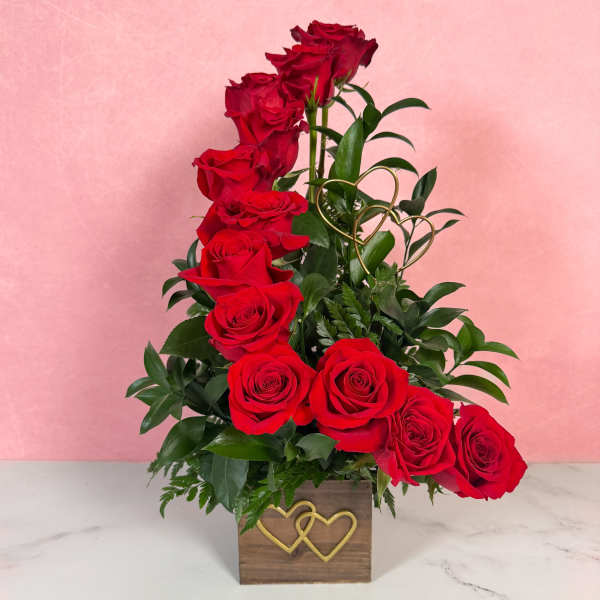 Red roses arranged in a wooden box with gold heart accents