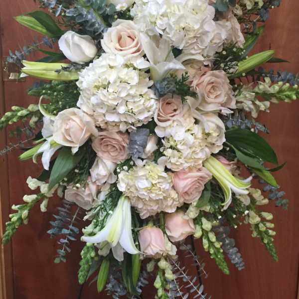 Large white and blush floral standing spray with lilies, roses, and hydrangeas