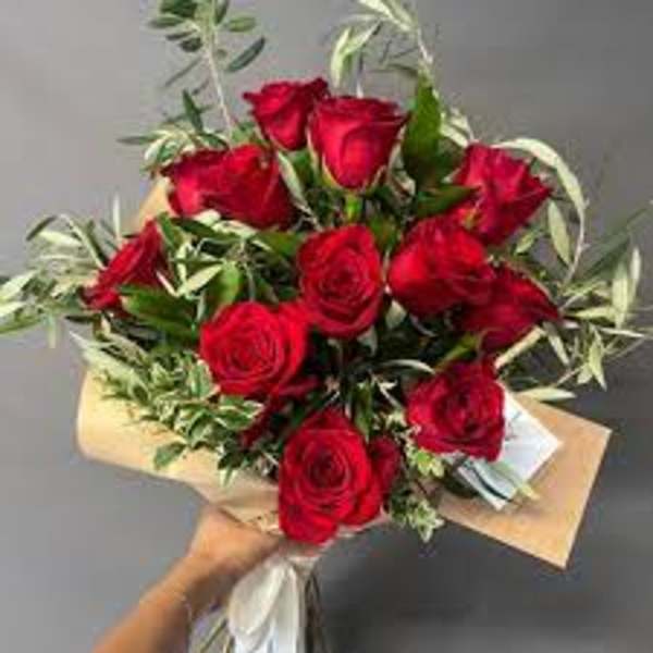 Bouquet of red roses with variegated greenery wrapped in paper