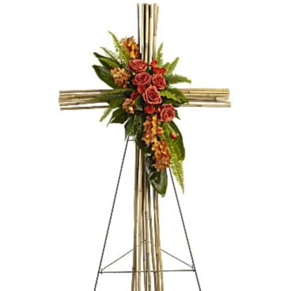 Tall bamboo cross spray with orange roses and orchids on a metal easel